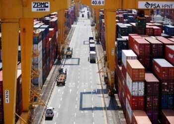 A truck driver stands next to his truck as he gets ready to transport a shipping container at Pusan Newport Terminal in Busan, South Korea, July 1, 2021.