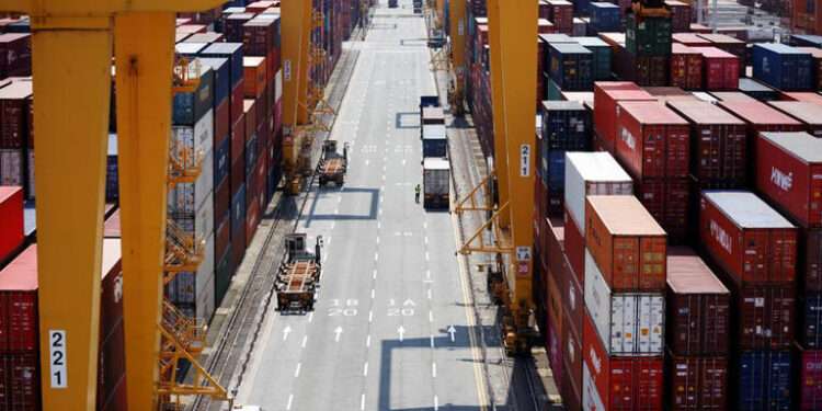 A truck driver stands next to his truck as he gets ready to transport a shipping container at Pusan Newport Terminal in Busan, South Korea, July 1, 2021.