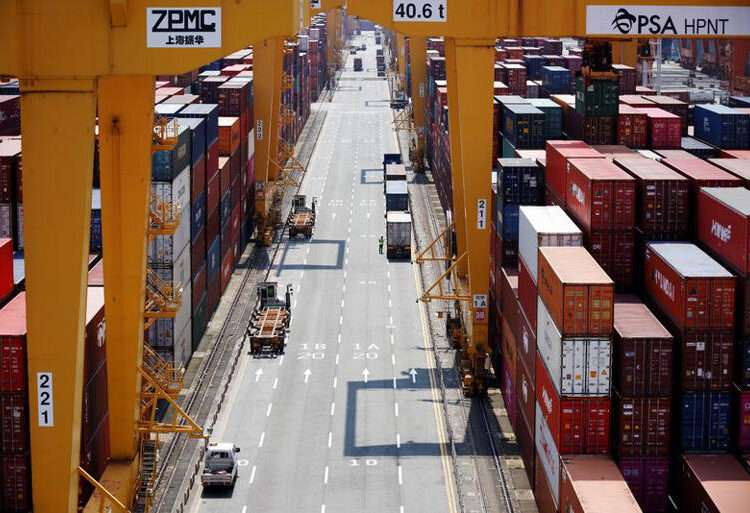 A truck driver stands next to his truck as he gets ready to transport a shipping container at Pusan Newport Terminal in Busan, South Korea, July 1, 2021.