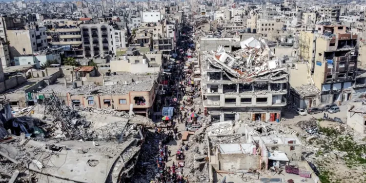 A drone view shows Palestinians walking at a street market near buildings damaged and destroyed during the Israeli offensive, amid the Israel-Hamas ceasefire in Gaza City, February 17, 2025.