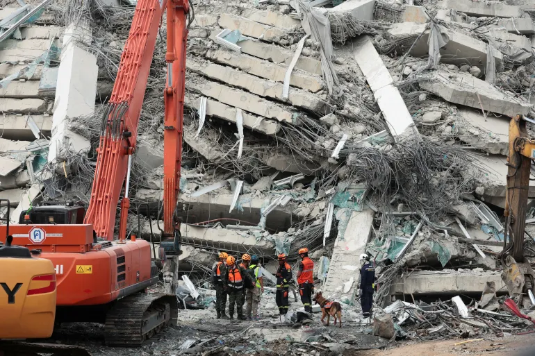 Rescuers work with a K9 dog at the site of a building that collapsed following a strong earthquake, in Bangkok, Thailand, on Sunday