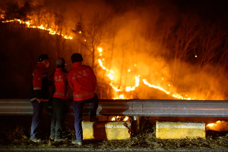 Korea Forest Service personnel observe a wildfire from the side of a road in Andong province on March 27, 2025 as South Korea Ravaged By Largest Wildfires On Record