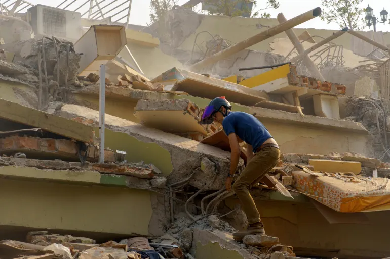 A man walks the rubble of a building that collapsed following a strong earthquake, in Mandalay, Myanmar as Hospitals In Myanmar Struggle With Influx Of Injured People