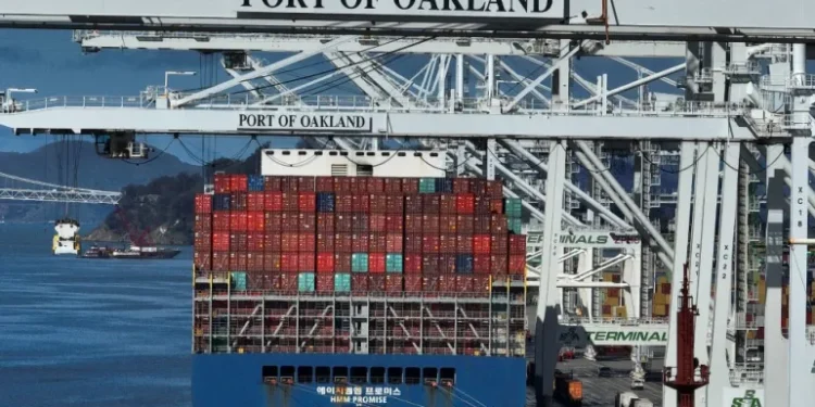 A shipping crane stands over a container ship at the Port of Oakland in Oakland, California