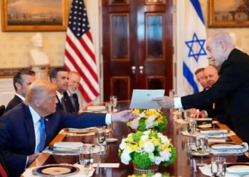 Israel's Prime Minister Benjamin Netanyahu hands President Donald Trump a folder during a meeting in the Blue Room of the White House, Monday,