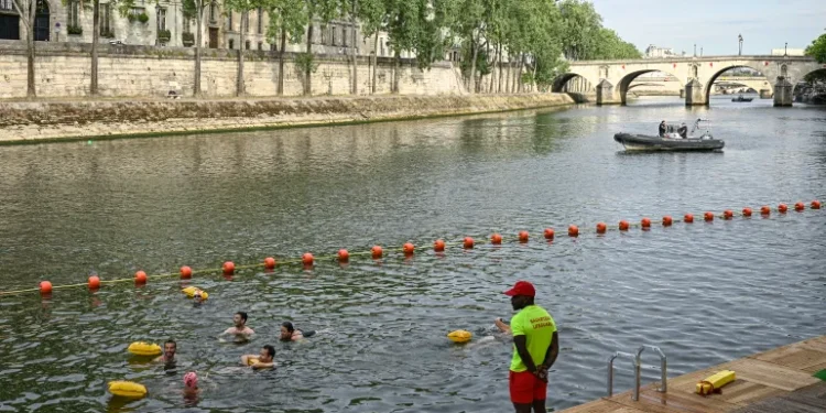 A lifeguard stands on duty as people swim at the Pont Marie safe bathing site on the River Seine on its opening day, in Paris, France on July 5, 2025.