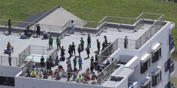 An aerial photo shows people gathered on the rooftops of buildings near the coast in Oamishirasato City, Chiba Prefecture, Japan, on Wednesday.