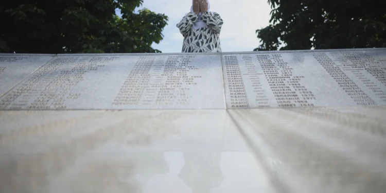 A Bosnian Muslim woman mourns next to a monument with the names of the victims of Srebrenica genocide, at the Memorial Center in Potocari, Bosnia, Friday, July 11, 2025.