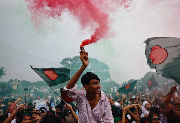 Bangladesh Marks Anniversary Of Hasina’s Ouster 1 People use coloured smoke and wave flags as they celebrate the one year anniversary since student-led protests ousted Bangladesh's former Prime Minister Sheikh Hasina, at Manik Mia Avenue, outside of the parliament building, in Dhaka, Bangladesh, August 5, 2025.