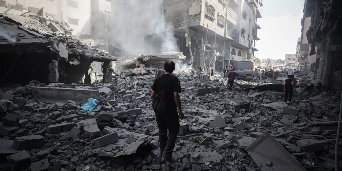 Palestinians walk through debris after an Israeli attack near Abbas Junction in Gaza City on Friday.