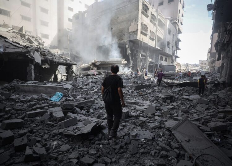 Palestinians walk through debris after an Israeli attack near Abbas Junction in Gaza City on Friday.