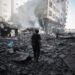 Palestinians walk through debris after an Israeli attack near Abbas Junction in Gaza City on Friday.