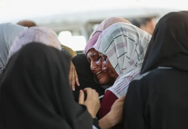 Palestinian women grieve for a slain loved on outside Gaza City’s al-Shifa