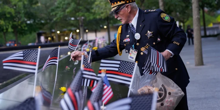Sam Pulia places flags on names inscribed in the 9/11 Memorial before the start of a ceremony commemorating the 24th anniversary of the Sept. 11, 2001, attacks, Thursday, Sept. 11, 2025, in New York.