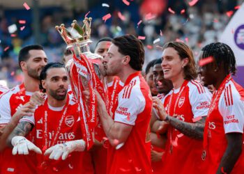 Declan Rice kisses the Premier League trophy while celebrating with his Arsenal teammates at Selhurt Park