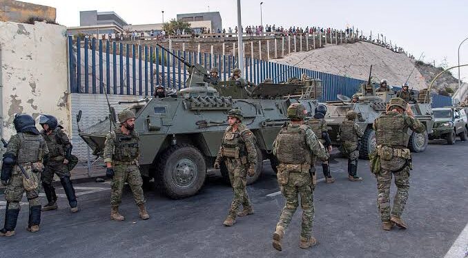 Spain Deploys Military to Ceuta as Thousands of Migrants Cross From Morocco 1 Spanish military stands at the border between the Spanish enclave of Ceuta and Morocco,