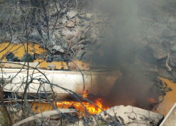 A tanker truck lies overturned and ablaze in the river below Birimso Bridge on the Accra-Kumasi highway, following the multi-vehicle pile-up that blocked traffic in both directions.