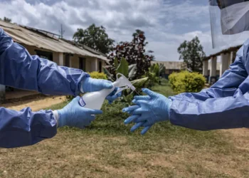 Health worker in personal protective equipment (PPE) undertaking sanitation measures