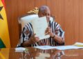 President John Dramani Mahama holds up the Customs Act, 2026, the most voluminous of the ten laws he assented to, at the Presidency in Accra. Photo: The Presidency