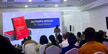 Dr Joyce Manyo speaks alongside a display of her newly launched book, Political Branding in Ghana, during the event's author's speech segment.