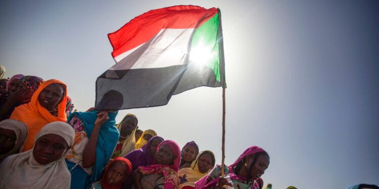 UN Warns Sudan War’s Consequences Will Be Long-Lasting 1 Sudanese women wave the national flag during a pro-democracy rally