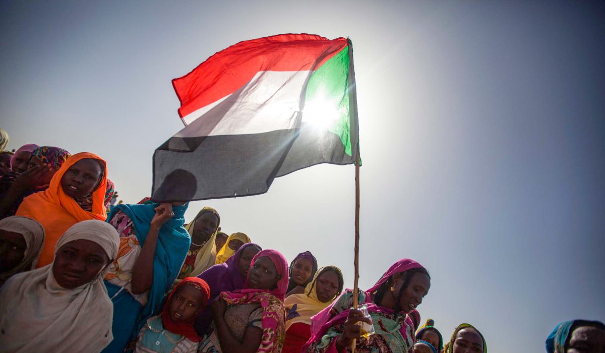 Sudanese women wave the national flag during a pro-democracy rally