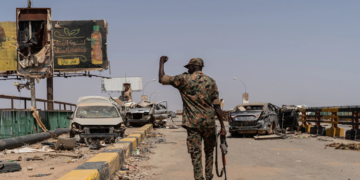 A soldier from the Sudanese Armed Forces (SAF) walking across the heavily damaged Shambat Bridge in Khartoum, Sudan