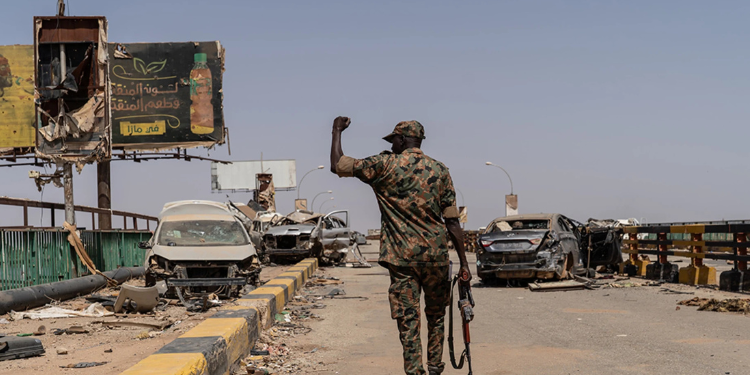 A soldier from the Sudanese Armed Forces (SAF) walking across the heavily damaged Shambat Bridge in Khartoum, Sudan