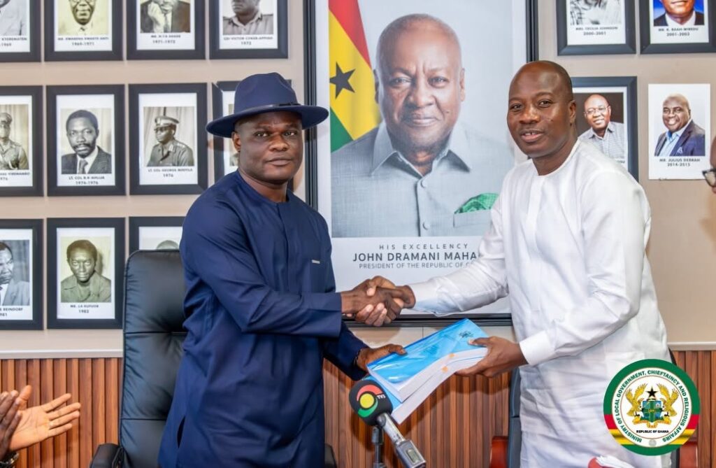 Mahama Ayariga: Assemblies Must Raise Their Own Revenue to Fix Cities 4 Ayariga receives handover documents from Ahmed Ibrahim, MP for Banda and immediate past Local Government Minister, beneath a portrait of President Mahama.