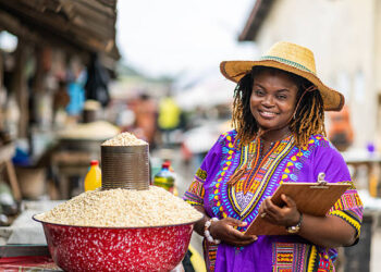 SMEs Move Into 24-Hour Economy's Jobs Debate 5 Portrait of Local African traditional woman entrepreneur, small business owner, SME, holding a clipboard at her outdoor market stall.