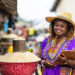 Portrait of Local African traditional woman entrepreneur, small business owner, SME, holding a clipboard at her outdoor market stall.