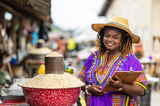 Portrait of Local African traditional woman entrepreneur, small business owner, SME, holding a clipboard at her outdoor market stall.
