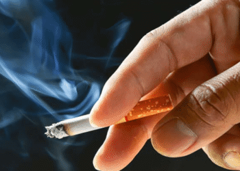 A hand holding a lit cigarette with a burning tip