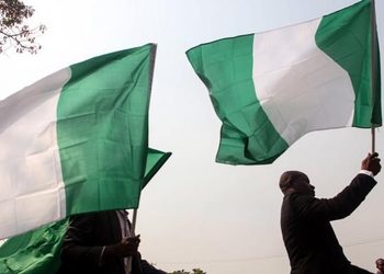 UN Reports 113 Million Nigerians Face Multidimensional Poverty 2 The green and white flag with the national coat of arms of Nigeria being waved