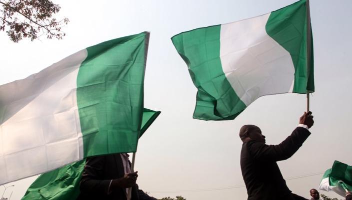 Protests Erupt in Nigeria Following Detainee Miners’ Deaths in Custody 2 green and white flag with the national coat of arms of Nigeria being waved during an outdoor gathering or protest 1