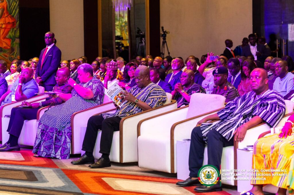 President Mahama studies the conference programme among government officials and delegates at the National Conference on Housing Finance on October 7, 2026. Photo credit: Ministry of Local Government, Chieftaincy and Religious Affairs (its watermark appears on the image)